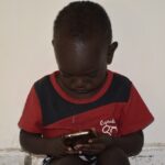 A child looks closely at a smartphone screen.