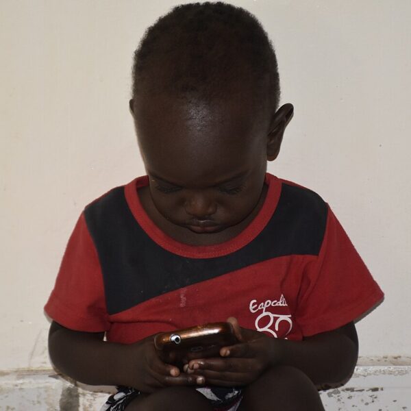 A child looks closely at a smartphone screen.