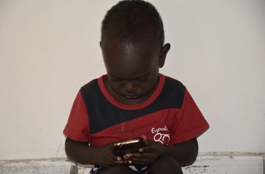 A child looks closely at a smartphone screen.