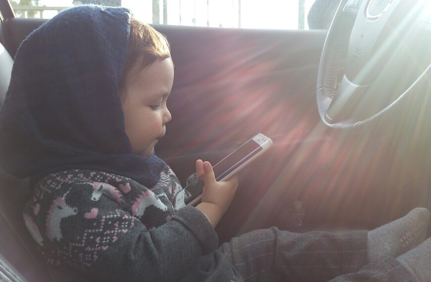 A child holds a cellphone, the kind of device a parent supervises with Google Family Link.