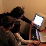 Two children sit together at a computer, a common setup for games like Roblox.