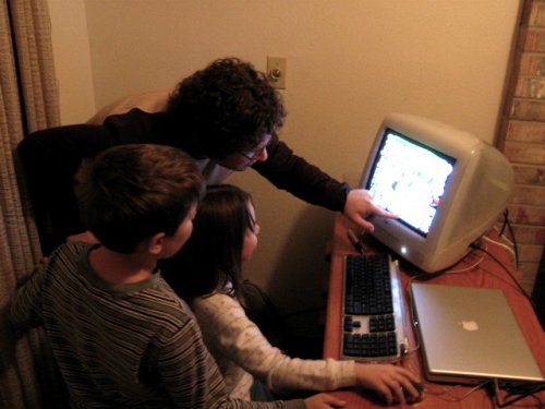 Two children sit together at a computer, a common setup for games like Roblox.